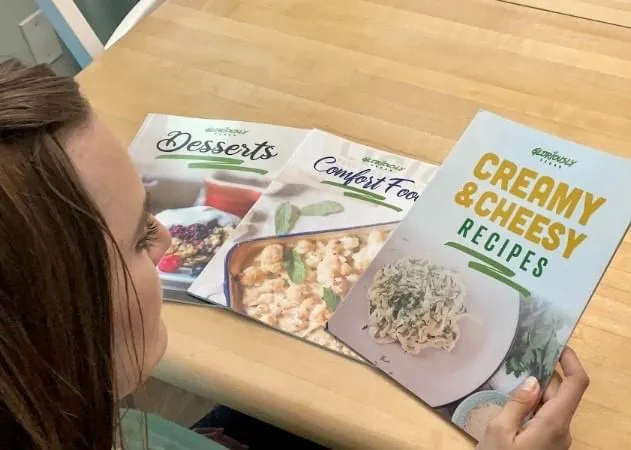 Woman holding 3 free cookbooks